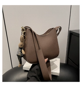 Detail of dark brown pebble leather shoulder bag with cute rabbit charm and gold zipper
