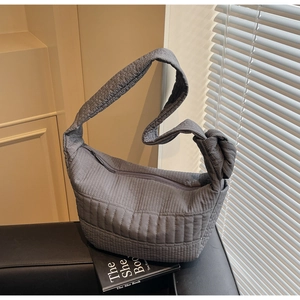 Macro view of grey quilted nylon shoulder bag with decorative knot strap detail