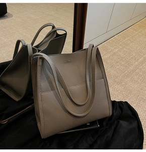 Detail of taupe litchi grain leather tote bag showing front pocket and dual straps
