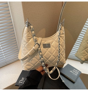 Detail of quilted diamond pattern and silver twist lock closure on cream leather bag
