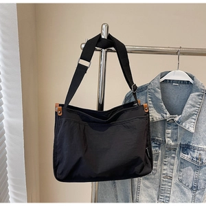 Detail of black canvas tote bag with brown leather trim and adjustable shoulder strap