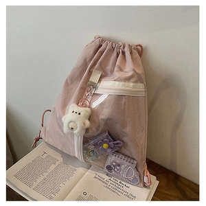 Detail of pink canvas backpack with transparent front pocket and cute white bear charm