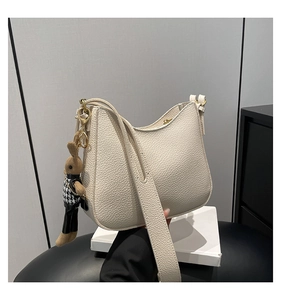 Detail of cream leather hobo bag with wide shoulder strap and cute bunny charm pendant