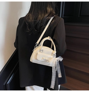 Detail of cream white bowling bag with bow pocket and delicate white lace ribbon accent