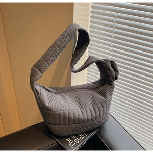 Detailed view of the soft quilted texture and knotted shoulder strap on the grey crescent bag