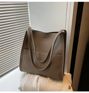 Detailed macro view of the premium lychee pattern leather texture on a beige tote bag