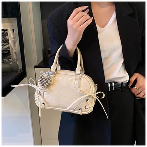 Vue détaillée du sac Boston crème avec nœuds, œillets et charm en forme de cœur