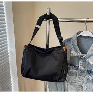 Close-up of black canvas crossbody bag with adjustable strap and side leather details