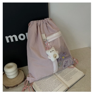 Detail of pink drawstring backpack with transparent PVC pocket and cute plush bear charm
