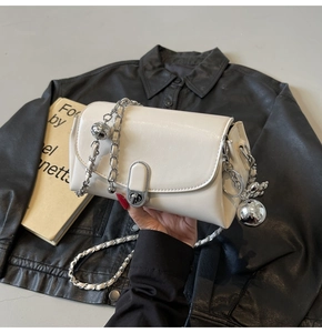 Detail of off-white faux leather square bag with silver chain strap and large ball charm