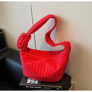 Macro shot of red quilted nylon bag showing knot detail and soft texture on black book