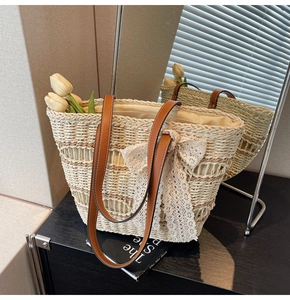 Detail of hand-woven straw tote with large cream lace bow and brown leather shoulder straps