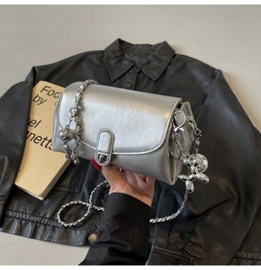 Detail of silver oil wax leather flap bag with metal chain and balloon dog charm