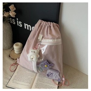 Detail of pink canvas drawstring backpack with clear window and plush bear accessory