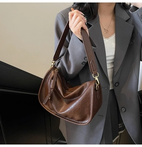 Detail of dark brown hobo bag with glossy crinkle leather and gold hardware