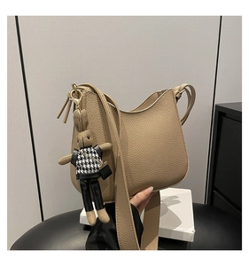 Detail of beige lychee leather hobo bag with wide strap and cute rabbit pendant
