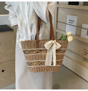 Detailed straw tote bag with brown leather strap and white lace bow decoration