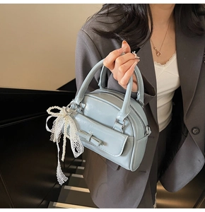 Close-up of light blue bowling bag with lace pearl charm and elegant bow detail