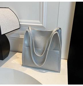 Detail of silver pebble grain leather tote bag with white piping and front pocket