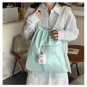 Detail of mint green drawstring backpack with mesh pocket and cute bear accessory