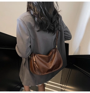 Close-up of brown vintage leather saddle bag with adjustable strap and gold buckle