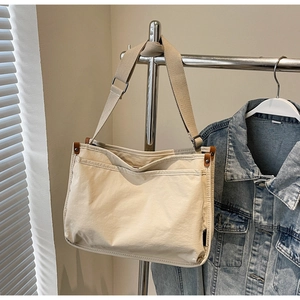 Detail of beige canvas tote with wide adjustable strap and silver metal buckle