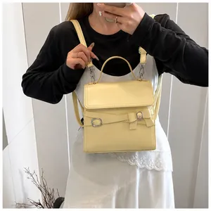 Détail d'une besace en cuir jaune clair avec décor de nœud et boucles argentées