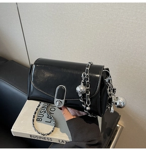 Close-up of glossy oil wax leather surface with silver oval twist lock and chain strap