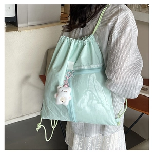 Detail of mint green drawstring backpack with front zipper pocket and plush bear charm