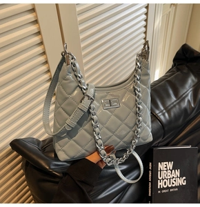Detail of light blue quilted leather bag with silver metal buckle and chain strap