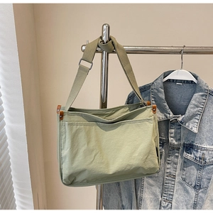Detail of light green canvas tote bag with adjustable wide strap and leather accents