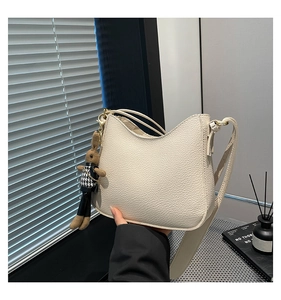 Détail du sac seau en cuir grainé blanc crème avec pendentif lapin et large bandoulière