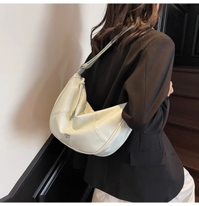Vue détaillée du sac demi-lune blanc cassé avec surpiqûres et logo argenté sur l'épaule