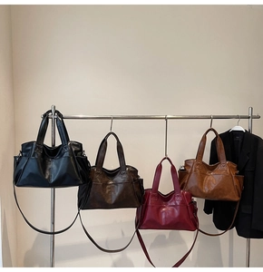 Row of large leather tote bags in four colors hanging on a stainless steel rack