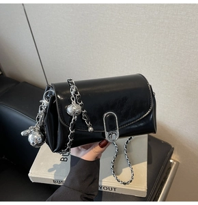 Detail of glossy black oil wax leather bag with silver chain and cute rabbit charm