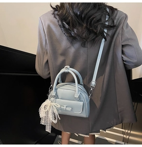 Detail showing baby blue mini bowling bag with bow pocket and lace pearl pendant charms