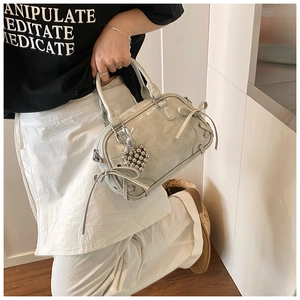 Détail du nœud décoratif et du charme en cœur sur ce sac Boston argenté brillant