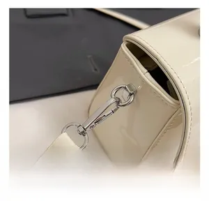 Détail du crochet métallique argenté et des coutures sur le sac en cuir verni blanc crème