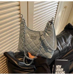 Detailed view of light blue quilted chain bag with silver lock and metallic texture