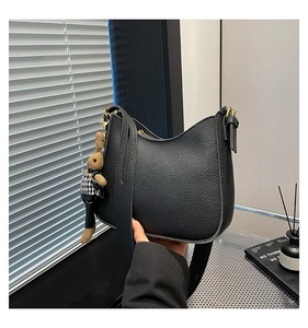 Gros plan sur la texture du cuir noir grainé et le zip doré de ce sac hobo tendance