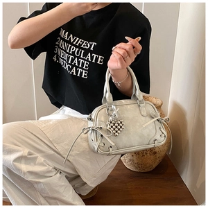 Détails du sac Boston argenté avec nœud, œillets métalliques et pendentif cœur