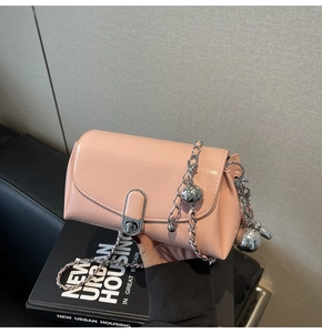 Detailed view of light pink glossy leather bag with silver chain and ball ornaments