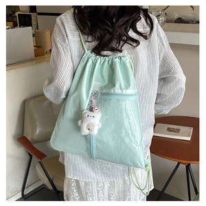 Detail of mint green drawstring backpack with mesh pocket and cute bear pendant charm