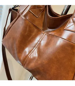 Close-up of vintage brown leather tote bag showing high-quality texture and side pocket detail