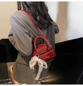 Detail of red patent leather bowling bag with pearl lace charm and shoulder strap