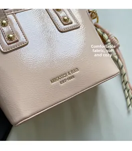 Detail of glossy patent leather bucket bag with gold studs and woven tassel charm