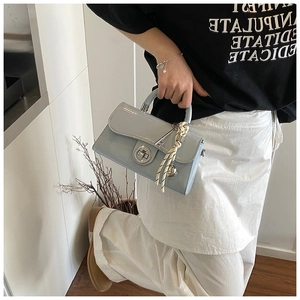Détail du sac à main en cuir verni bleu clair avec fermoir rotatif et anse foulard