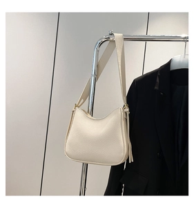 Gros plan du sac bandoulière en cuir grainé blanc cassé avec pompon décoratif