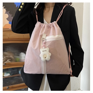 Detailed view of pink drawstring backpack with transparent pocket and plush bear pendant