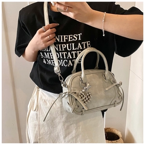Détail d'un sac Boston argenté avec nœud décoratif et bandoulière réglable pratique